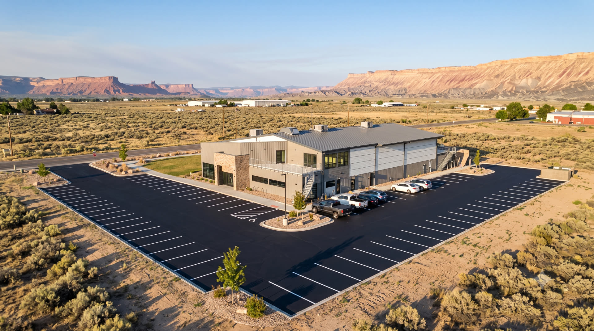 Freshly seal-coated parking lot with crisp white striping in front of an office building, red rock mesas in the distance